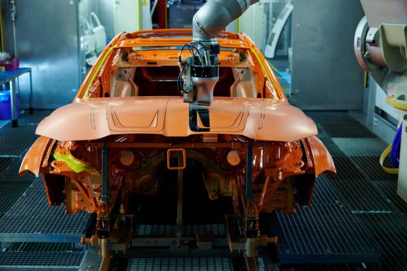 Ein Roboter appliziert die individuelle Bicolor-Lackierung und M4-Kennzeichnung auf der Motorhaube eines M4 Coupé